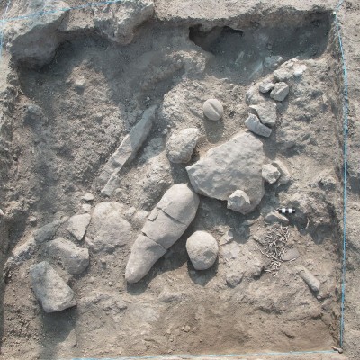 Figure 3. View over square E6.1, indicating artefact cluster 21—a cache of dentalium fragments—in the lower right; farther towards the right-hand corner is a zoomorphic basaltic pestle (RN 140049); then proceeding clockwise, a basaltic handstone (RN 140048), a phalliform figurine (RN 140225) and a basaltic shaft-straightener (RN 140047).